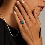 Luxury gemstone ring featuring vibrant colored stone with dazzling white stone halo des