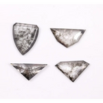 Four salt and pepper lab grown diamonds in shield, trillion, and geometric fancy cuts with natural grey inclusions, displayed on white background as loose ethical conflict-free stones for custom jewelry.