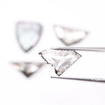 Four salt and pepper lab grown diamonds in shield, trillion, and geometric fancy cuts with natural grey inclusions, displayed on white background as loose ethical conflict-free stones for custom jewelry.