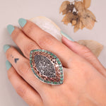 Victorian marquise black diamond ring with an emerald halo in a sterling silver cocktail setting.