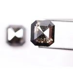 Emerald cut lab grown salt and pepper diamond with geometric step cut facets featuring bold black and smoky inclusions, octagonal shape, ethical sustainable gemstone.