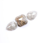Three natural salt and pepper diamonds featuring two pear rose cut stones and one octagon step cut center diamond with visible inclusions and raw earthy tones, ideal for bespoke engagement ring or artisan jewelry design.