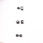 Six natural black diamonds in geometric cuts including star, kite, emerald rectangle, pentagon, and round brilliant shapes displayed on white background.
