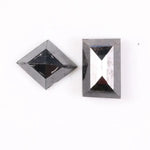 Pair of natural black diamonds featuring a shield-shaped cut and an elongated baguette-style cut, loose matching set with faceted surfaces for custom fine jewelry design.