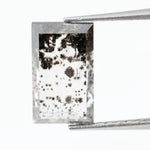 Rectangular step cut lab grown diamond featuring dramatic black dendritic inclusions in a salt and pepper pattern, creating a unique one of a kind modern alternative diamond with striking natural looking carbon formations inside a clear faceted stone.
