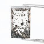 Rectangular step cut lab grown diamond featuring dramatic black dendritic inclusions in a salt and pepper pattern, creating a unique one of a kind modern alternative diamond with striking natural looking carbon formations inside a clear faceted stone.