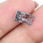 Rectangular step cut lab grown diamond featuring dramatic black dendritic inclusions in a salt and pepper pattern, creating a unique one of a kind modern alternative diamond with striking natural looking carbon formations inside a clear faceted stone.