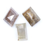 Three natural diamonds including a pink included fancy cut diamond, a golden brown heavily included diamond, and a clear step cut rectangular natural diamond displayed on a white background.