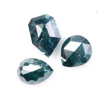 Three natural teal blue diamonds featuring pear, oval, and shield cuts with visible galaxy-like inclusions, rare salt and pepper natural diamonds ideal for custom jewelry design