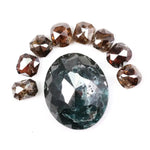 Large natural green diamond surrounded by fancy cognac brown natural diamonds arranged in a semicircle, showcasing rare earth-mined colored diamonds with visible natural inclusions and unique faceting.