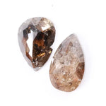 Pair of natural brown diamonds showing raw crystal inclusions and faceted pear shapes with cognac tones, genuine earth mined gemstones with natural internal patterns and rough texture ideal for collectors, jewelers, and natural diamond enthusiasts.
