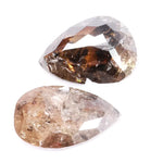 Pair of natural brown diamonds showing raw crystal inclusions and faceted pear shapes with cognac tones, genuine earth mined gemstones with natural internal patterns and rough texture ideal for collectors, jewelers, and natural diamond enthusiasts.