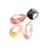 Collection of natural fancy color diamonds including pink, yellow, champagne and cognac loose diamonds with faceted cuts displayed on white background for fine jewelry and gemstone collecting.