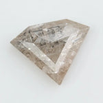 Close-up of a faceted lab grown diamond with visible natural-style inclusions, brilliant cut geometry, and soft champagne hue on a clean white background