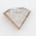 Close-up of a faceted lab grown diamond with visible natural-style inclusions, brilliant cut geometry, and soft champagne hue on a clean white background