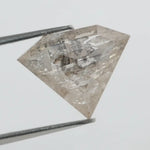 Close-up of a faceted lab grown diamond with visible natural-style inclusions, brilliant cut geometry, and soft champagne hue on a clean white background