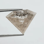 Close-up of a faceted lab grown diamond with visible natural-style inclusions, brilliant cut geometry, and soft champagne hue on a clean white background