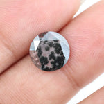 Round cut lab grown salt and pepper diamond featuring bold black dendritic inclusions in a transparent stone, faceted for brilliance and showcasing a unique natural pattern