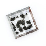 Clear lab-grown diamond with striking black natural-style inclusions inside a polished rectangular crystal, showcasing a unique modern gemstone aesthetic