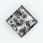 Clear lab-grown diamond with striking black natural-style inclusions inside a polished rectangular crystal, showcasing a unique modern gemstone aesthetic