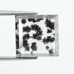 Clear lab-grown diamond with striking black natural-style inclusions inside a polished rectangular crystal, showcasing a unique modern gemstone aesthetic