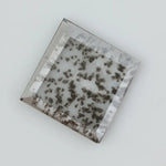 Square step-cut lab grown diamond with dramatic black salt and pepper inclusions, showcasing a unique geometric faceted structure and modern ethical gemstone design