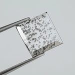 Square step-cut lab grown diamond with dramatic black salt and pepper inclusions, showcasing a unique geometric faceted structure and modern ethical gemstone design