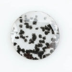 Close-up of a round, lab-grown diamond with black and white speckled inclusions, sparkling facets, and jewelry-grade clarity, ethically sourced and crafted for fine jewelry