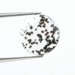Close-up of a round, lab-grown diamond with black and white speckled inclusions, sparkling facets, and jewelry-grade clarity, ethically sourced and crafted for fine jewelry
