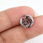 Close-up of a round, lab-grown diamond with black and white speckled inclusions, sparkling facets, and jewelry-grade clarity, ethically sourced and crafted for fine jewelry