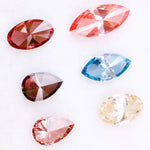 Six fancy color lab grown diamonds on white background including yellow oval cut, blue marquise cut, pink marquise cut, peach pear cut, deep red pear cut, and red oval cut brilliant stones for custom jewelry design.