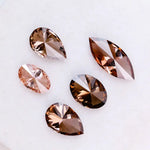 Five lab grown brown and champagne diamonds in pear, oval, and marquise cuts displayed on a white background, showcasing rich cognac tones and brilliant faceting for fine jewelry design.