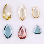 Six lab grown colored diamonds displayed on white background featuring pear, marquise and oval cuts in fancy yellow, champagne, blue and pink shades, ideal for custom engagement rings and fine jewelry settings.