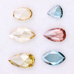 Six lab grown colored diamonds displayed on white background featuring pear, marquise and oval cuts in fancy yellow, champagne, blue and pink shades, ideal for custom engagement rings and fine jewelry settings.