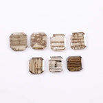 Emerald cut lab grown diamond featuring natural-inspired linear inclusions in a step cut octagonal shape, showcasing warm champagne tones and geometric internal patterns on a clean white background.