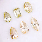 Six fancy yellow lab grown diamonds in pear, emerald, oval, and marquise cuts displayed on a white background, showcasing brilliant sparkle and canary color tones.