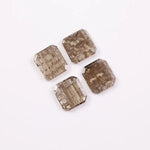 Four emerald-cut champagne lab grown diamonds with visible salt and pepper style inclusions, faceted step-cut stones in warm brown tones on white background