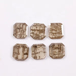 Six emerald cut octagonal lab grown diamonds featuring distinctive golden vein-like inclusions in a transparent champagne-toned base, displayed on a white background.