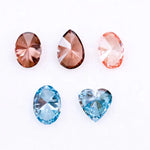 Five loose lab grown diamonds displayed on a white background, featuring three pink diamonds in oval, pear, and round cuts, alongside two vivid blue diamonds in heart and oval shapes, showcasing brilliant faceting and high clarity.