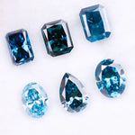 Six lab grown blue diamonds in emerald, oval and pear cuts displaying fancy deep ocean blue color arranged on white background for custom engagement ring and fine jewelry making.