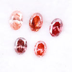 Five oval cut pink lab grown diamonds displayed on a white background, ranging in color from light blush pink to deep vivid rose and red tones, shown for color comparison and gemstone selection.
