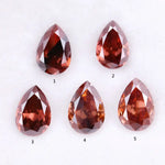 Five pear-shaped lab grown diamonds in fancy deep pinkish red color arranged on a white background, featuring brilliant faceting and teardrop cut for engagement rings and custom fine jewelry.