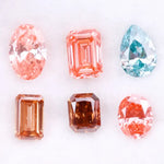 Lab grown fancy pink, peach, cognac and blue diamonds in oval, emerald and pear cuts displayed on white background, sustainable CVD created gemstones for fine jewelry.