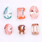 Lab grown fancy pink, peach, cognac and blue diamonds in oval, emerald and pear cuts displayed on white background, sustainable CVD created gemstones for fine jewelry.