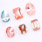 Lab grown fancy pink, peach, cognac and blue diamonds in oval, emerald and pear cuts displayed on white background, sustainable CVD created gemstones for fine jewelry.