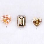 Three lab grown fancy color diamonds including pink heart cut, champagne emerald cut, and yellow heart shape loose diamonds for engagement ring and custom jewelry making