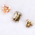 Three lab grown fancy color diamonds including pink heart cut, champagne emerald cut, and yellow heart shape loose diamonds for engagement ring and custom jewelry making