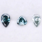 Three blue lab grown diamonds displayed on white background: pear cut light blue diamond (1), heart cut teal diamond (2), and deep blue pear shaped diamond (3), brilliant faceted loose stones for engagement ring or custom fine jewelry.