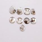 Assorted rose cut lab grown diamonds with natural-looking inclusions in oval, pear, round and cushion shapes arranged on white background for fine jewelry design.