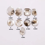 Assorted rose cut lab grown diamonds with natural-looking inclusions in oval, pear, round and cushion shapes arranged on white background for fine jewelry design.